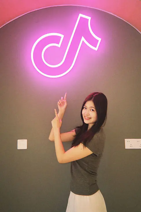 Ruohan standing beneath a glowing TikTok logo